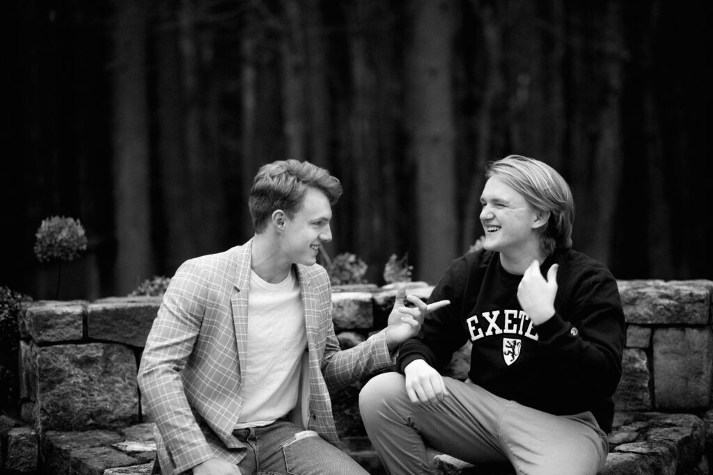 Black and white portrait of senior boy and his brother. Photographed in their backyard at home. Candid moment laughing. Photographed by Pierre Chiha Photographers