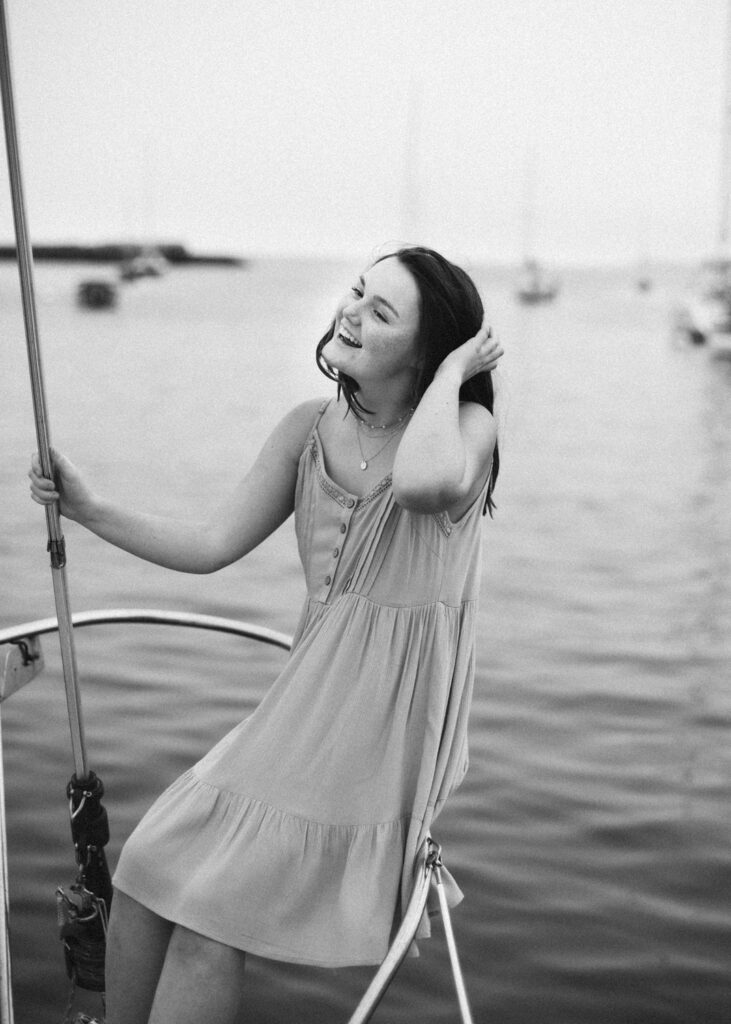 This senior portrait location is on a boat at the beach. The portrait is of a high school senior girl wearing a dress. It's in black and white. Photographed by Pierre Chiha Photographers
