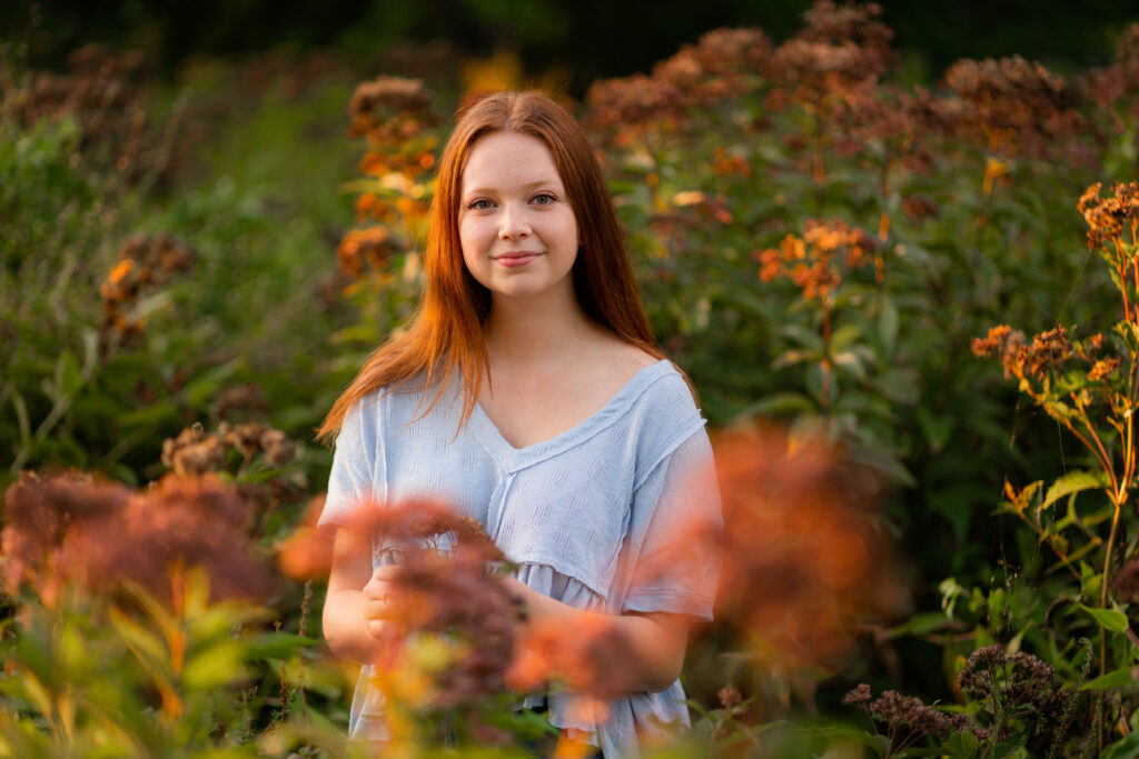 Senior portrait outside in nature surrounded by a field of flowers. The location is at the Old North Bridge in Concord, MA. Photographed by Pierre Chiha Photographers
